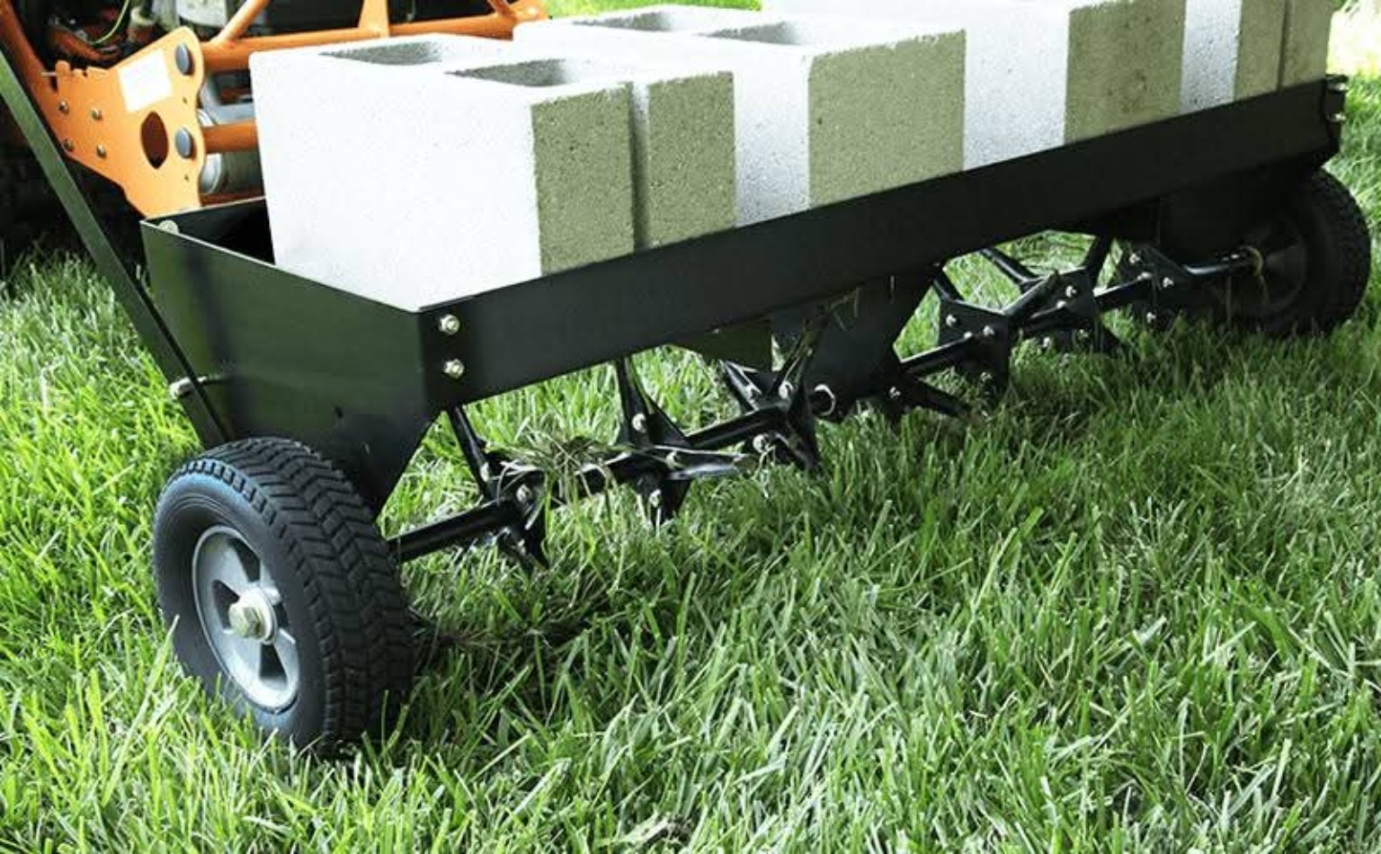 Tow-behind plug aerator working across a green lawn